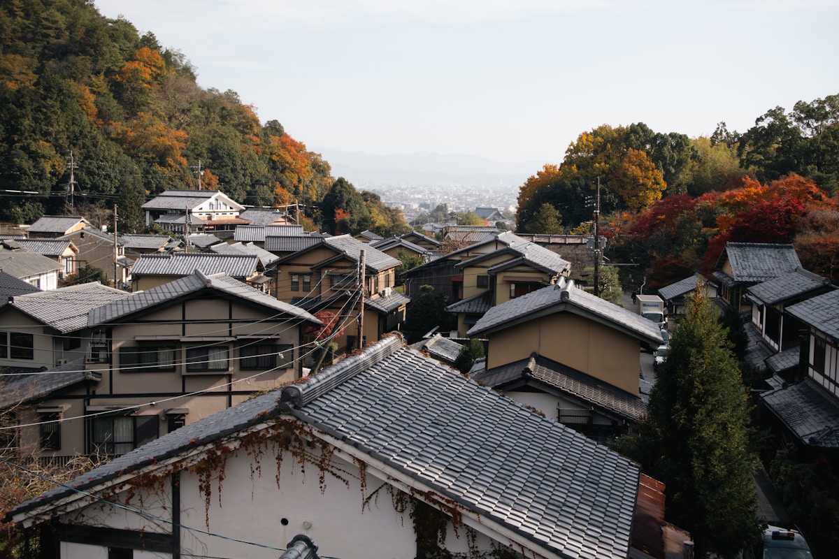 Traditional Japanese houses nestled on a forested hillside in autumn
