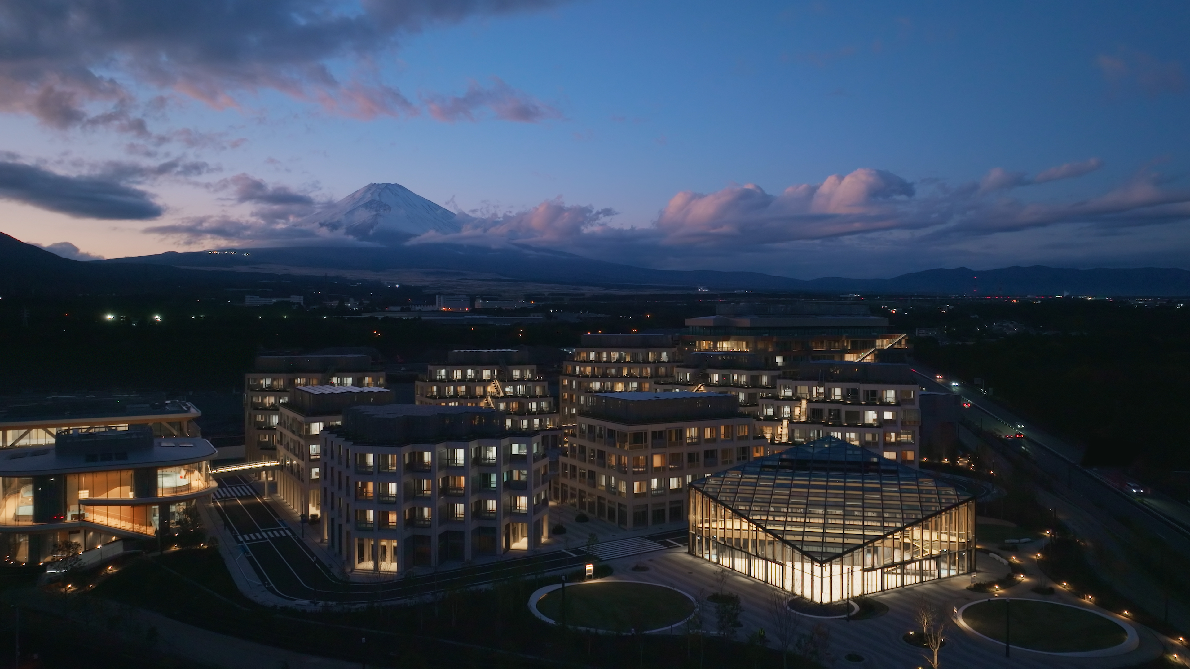 Toyota Woven City aerial view at dusk — the Phase 1 prototype community in Susono, Shizuoka Prefecture, with Mount Fuji silhouette. Photo: Toyota Motor Corporation