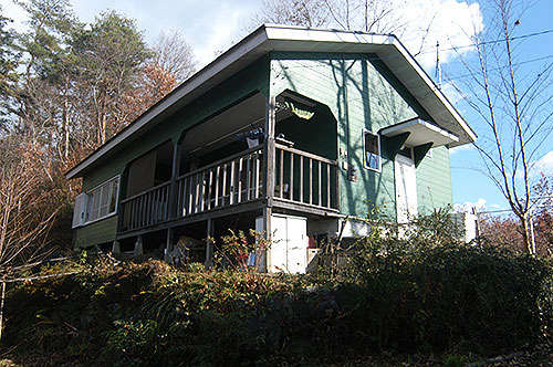A one-story house on a hill with lush greenery - Thumbnail 3